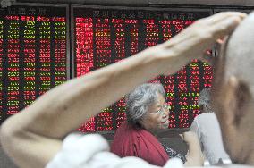 Investors watch quotation board at Beijing brokerage house