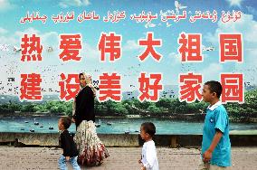 People walk by huge propaganda signboard in Urumqi, China