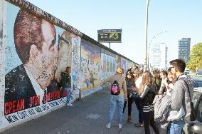 Tourists gather before Berlin Wall piece with "Kiss of Death" drawing