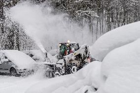 A bobcat with a snow cutter cleans a road, snowfall, wind, snow