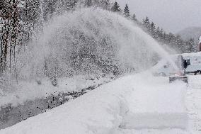 A man with a snow cutter cleans a road, snowfall, wind, snow