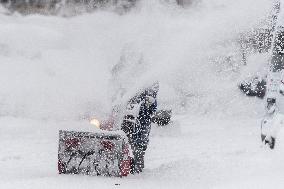 A man with a snow cutter cleans a road, snowfall, wind, snow