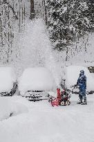 A man with a snow cutter cleans a road, snowfall, wind, snow