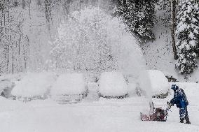 A man with a snow cutter cleans a road, snowfall, wind, snow