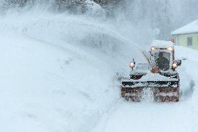 A snow cutter cleans a road, snowfall, wind, snow