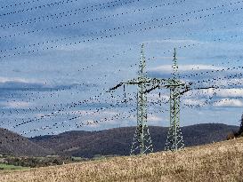 Double mast, power lines, wooded hills, sky with clouds