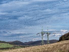 Double mast, power lines, wooded hills, sky with clouds