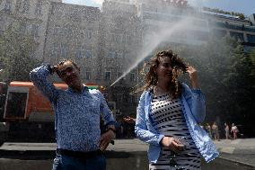 tank truck sprinkles by water the Wenceslas Square in Prague, man, woman