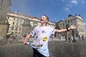 tank truck sprinkles by water the Hradcany Square in front of the Prague Castle, boy