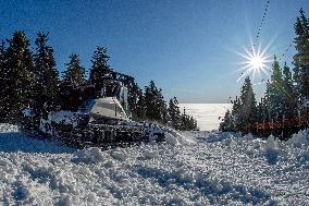 snowcat moves snow in ski resort, sun