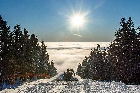 snowcat moves snow in ski resort, sun