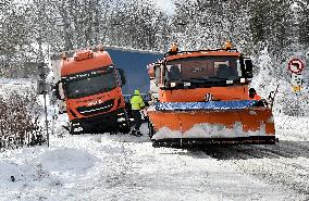 snowplow pulls a stranded truck on a snow covered road