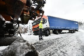 snowplow pulls a stranded truck on a snow covered road