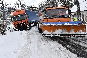 snowplow pulls a stranded truck on a snow covered road