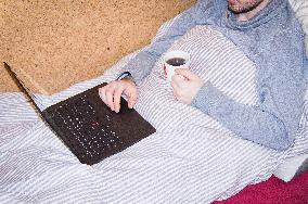 home office, young man, featherbed, bedding, laptop, notebook, cup of tea