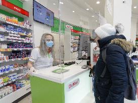 pharmacy, apothecary serves a customer through a plexiglass with a protective medical mask