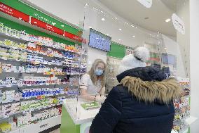 pharmacy, apothecary serves a customer through a plexiglass with a protective medical mask