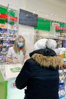 pharmacy, apothecary serves a customer through a plexiglass with a protective medical mask