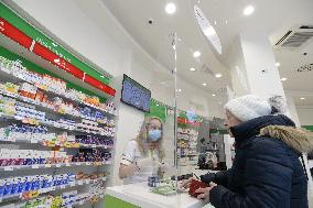 pharmacy, apothecary serves a customer through a plexiglass with a protective medical mask