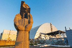 Chernobyl zone, restricted territory, Memorial to the Chernobyl liquidators with secure dome over the damaged Chernobyl nuclear reactor number 4
