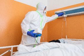 a medic in a protective suit checks a covid-19 patient