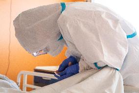 a medic in a protective suit tests a covid-19 patient