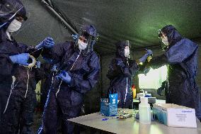 medics prepare to take samples for a covid-19 test from volunteers