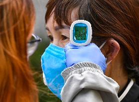 a medic checks temperature of a man during waiting to take a sample for a covid-19 test