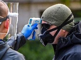 a medic checks temperature of a man during waiting to take a sample for a covid-19 test