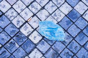 discarded face mask lies on the ground, pavement, pandemic, coronavirus, hazardous waste, fag end, cigarette stub