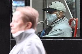 A woman without face mask pass tram passengers wearing face masks