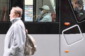 A woman without face mask pass tram passengers wearing face masks