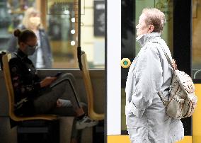 A woman without face mask pass tram passengers wearing face masks