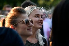 spectators watch a performance, woman, women, girl, girls, smile, smoke, sunglasses