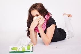 A beautiful young woman, lady, girl, cold, runny nose, headache, tissues, paper hankies, scarf, handkerchiefs, handkerchief, nose-blowing