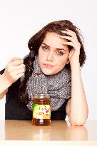 A beautiful young woman, lady, girl,  cold, runny nose, headache, cup of tea with honey, spoon, scarf.