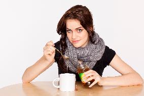 A beautiful young woman, lady, girl,  cold, runny nose, headache, cup of tea with honey, spoon, scarf.