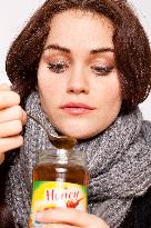 A beautiful young woman, lady, girl, cold, runny nose, headache, tea, honey, spoon, scarf.