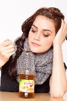 A beautiful young woman, lady, girl, cold, runny nose, headache, tea, honey, spoon, scarf.