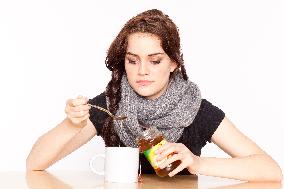 A beautiful young woman, lady, girl, cold, runny nose, headache, tea, honey, spoon, scarf.