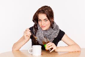 A beautiful young woman, lady, girl, cold, runny nose, headache, tea, honey, spoon, scarf.