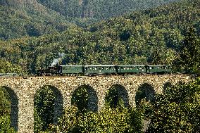 steam locomotive runs over railway stone viaduct