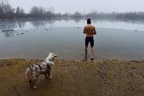 young man bathes in ice water in the natural swimming pool, dog