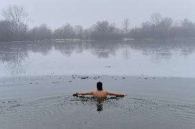 young man bathes in ice water in the natural swimming pool