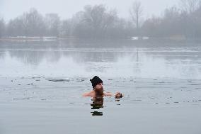 young man bathes in ice water in the natural swimming pool