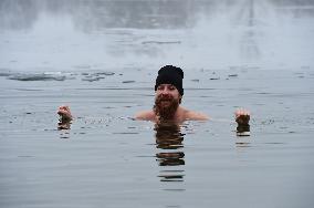 young man bathes in ice water in the natural swimming pool