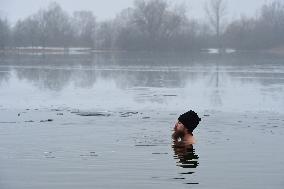 young man bathes in ice water in the natural swimming pool