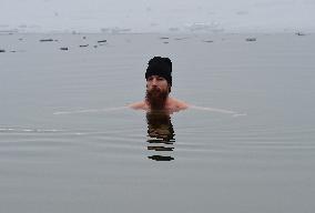 young man bathes in ice water in the natural swimming pool