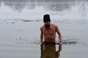 young man bathes in ice water in the natural swimming pool