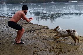 young man bathes in ice water in the natural swimming pool, dog